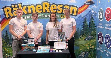 Fyra gymnasister i en monter där de visar upp ett spel. På skynket i montern står ordet "Räkneresan".