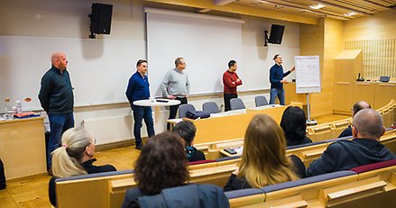 Fem personer står inför ett antal åhörare i en föreläsningssal.