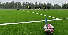 träning på en fotbollsplan med en fotboll i förgrunden