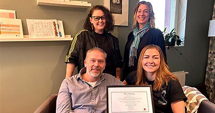 Fyra personer sitter och visar ett diplom