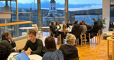 Ungdomar och vuxna sitter kring runda bord och samtalar